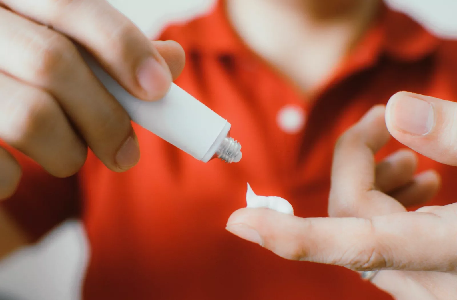 Glass bottle of azelaic acid and tube of tretinoin placed next to a clean white sink