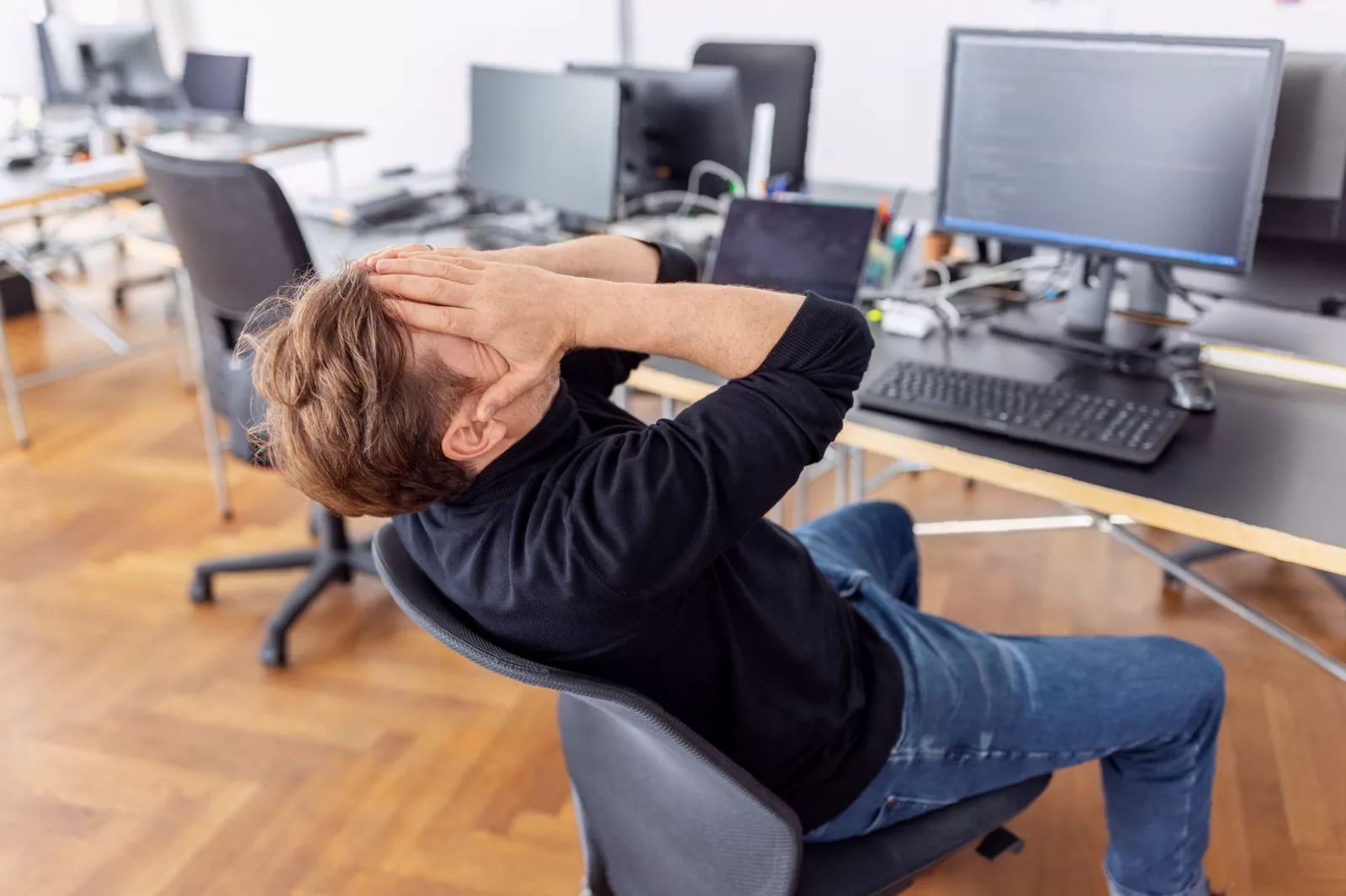 Employee standing by office washbasin with head down, visibly upset after leaving a cubicle