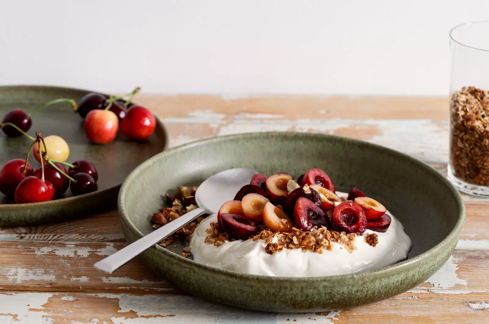 A close-up shot of egg whites being whisked in a ceramic bowl next to a container of Greek yoghurt