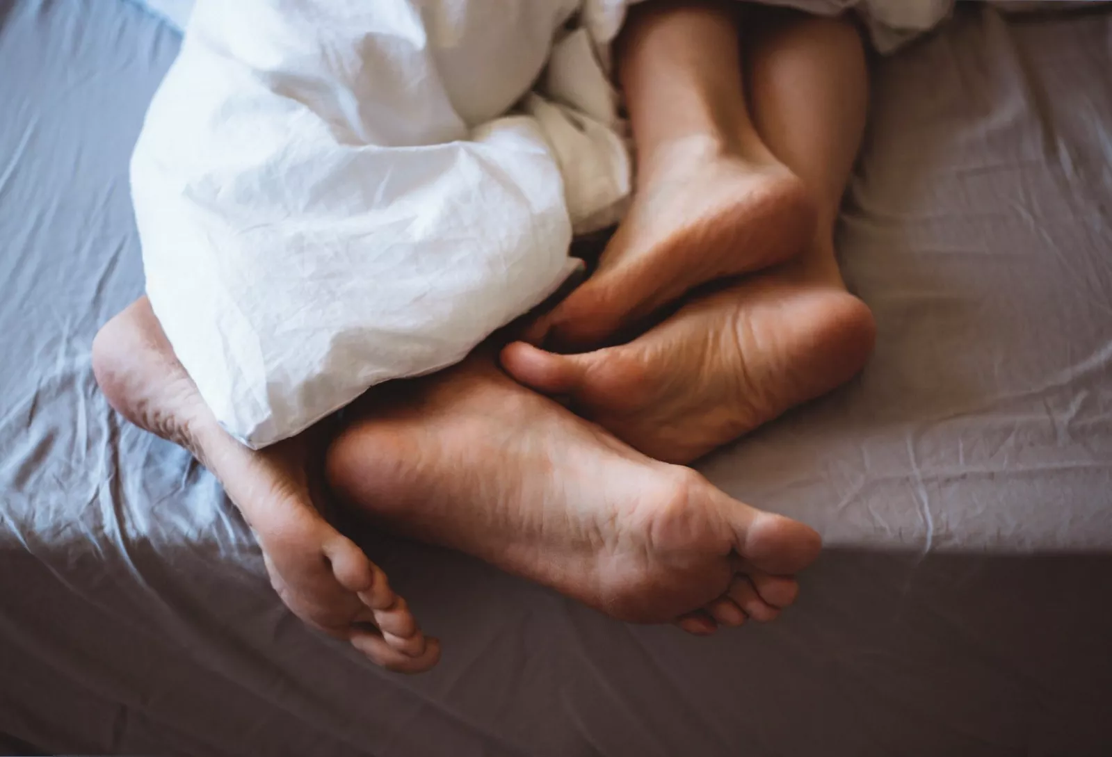 A couple in a bedroom looking concerned, with a bottle of water-based lubricant on the bedside table