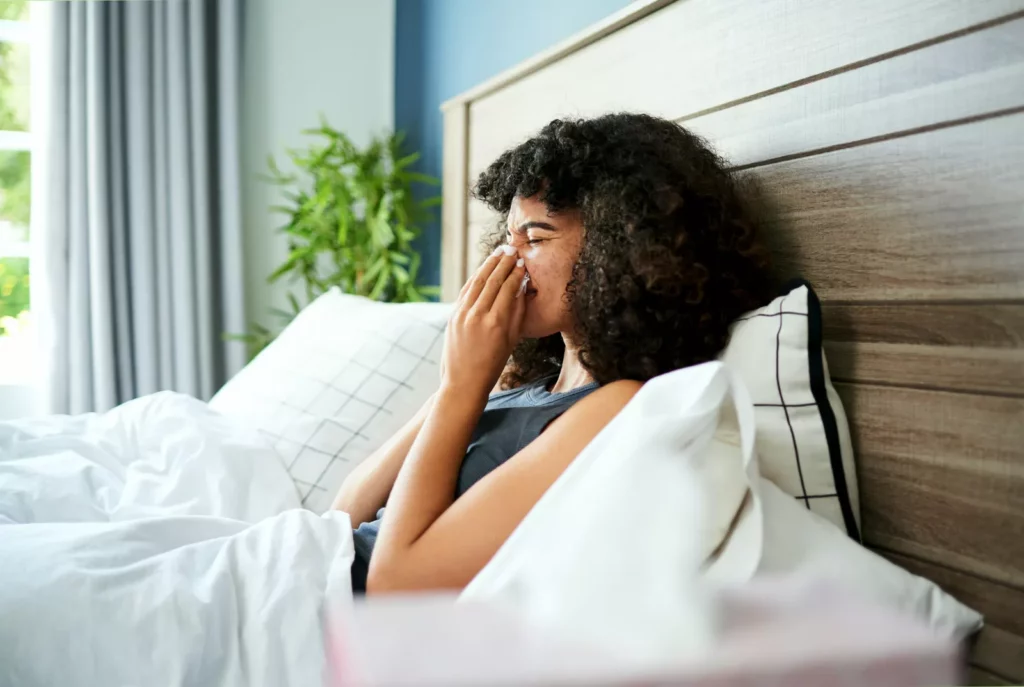A person holding a nasal decongestant spray bottle indoors