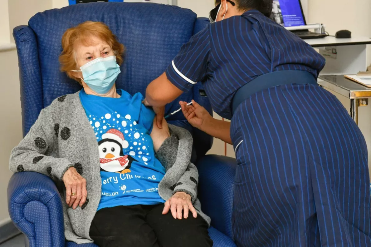 A person using a smartphone to book a vaccine appointment online.