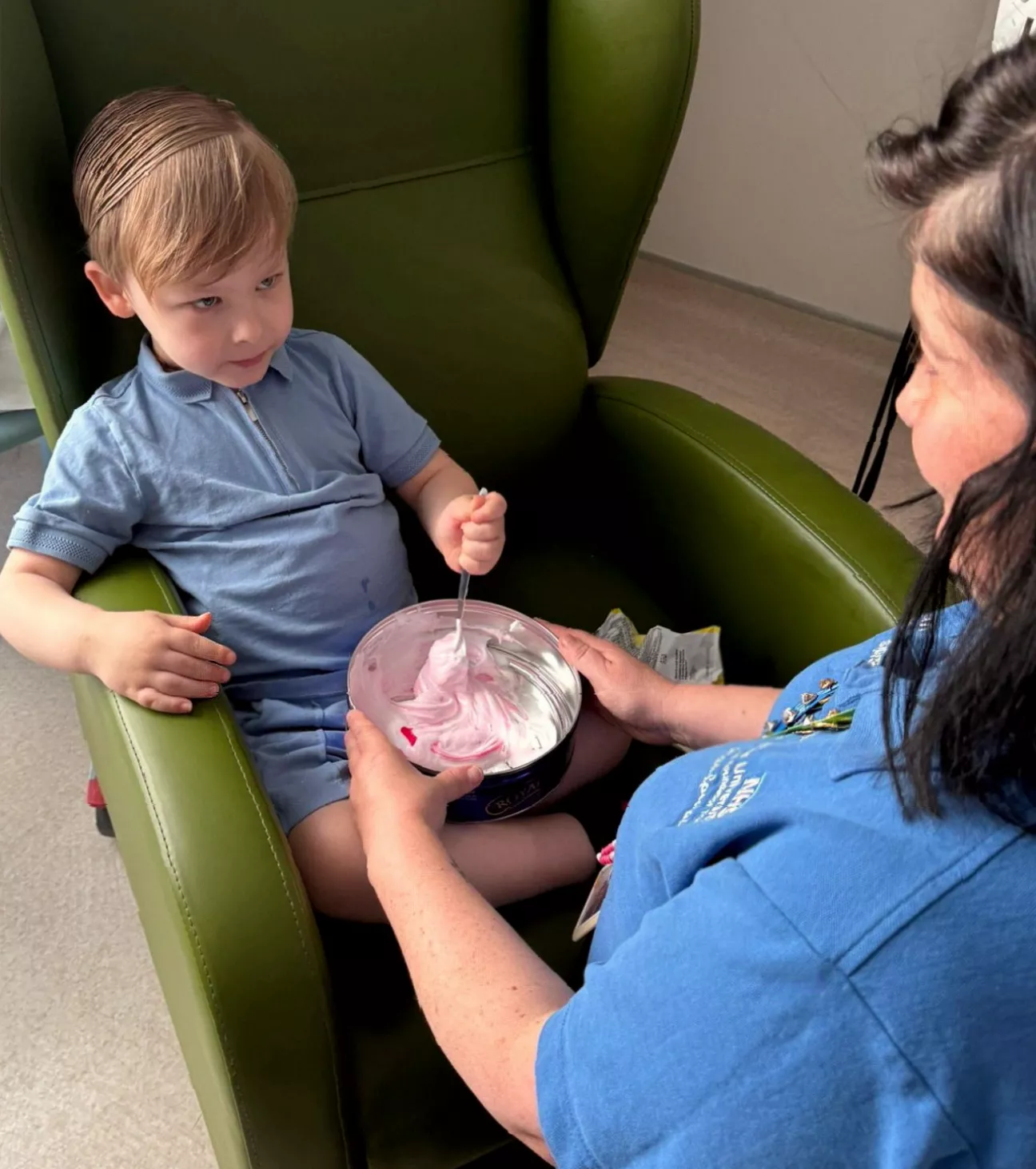 A hospital play therapist interacting with a paediatric patient during cancer treatment