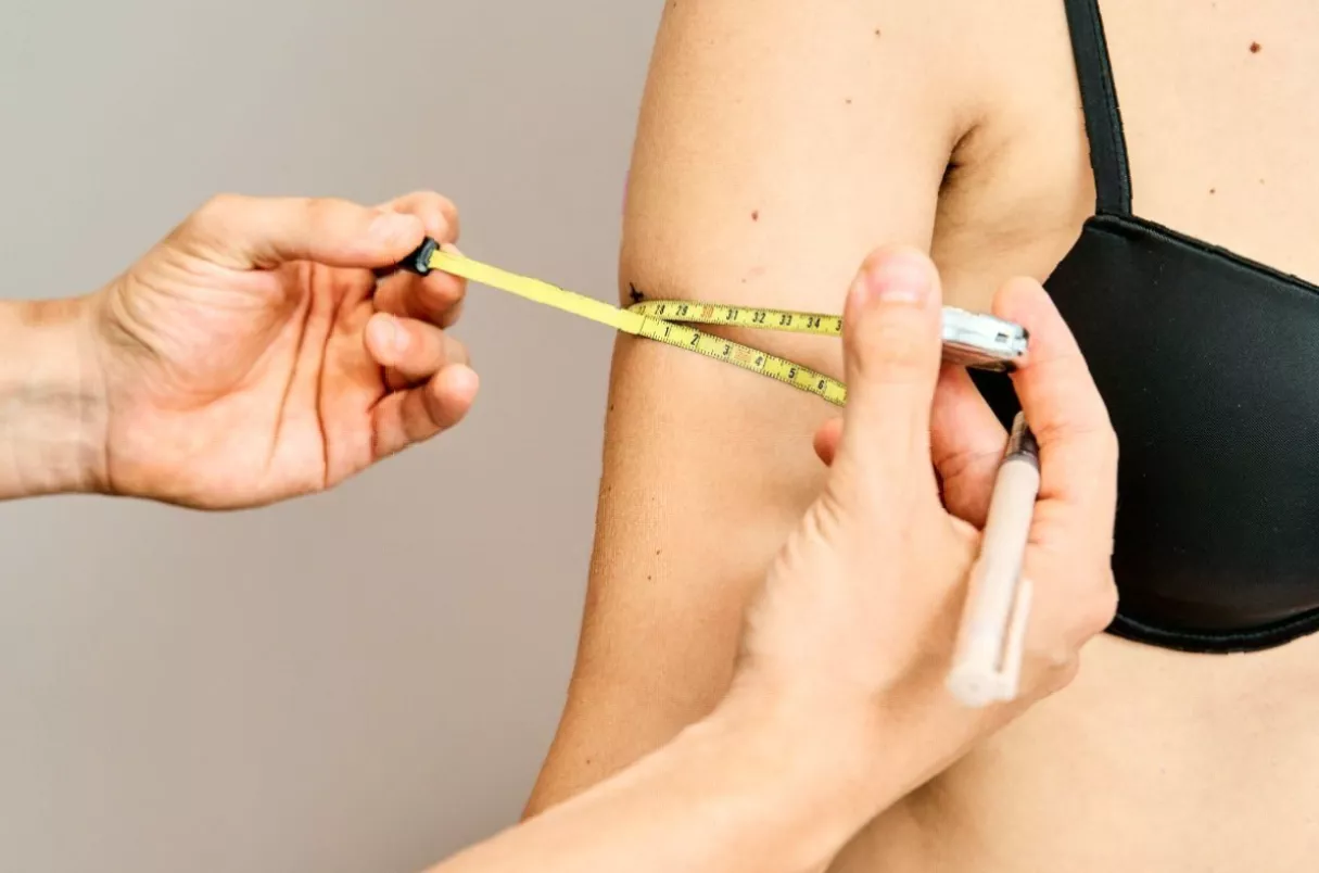 A person holding a prescription for weight loss medication in a UK pharmacy.