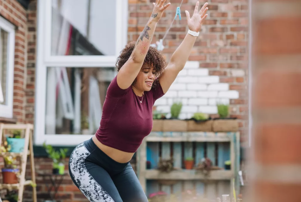 Woman performing a plié squat exercise in a living room setting
