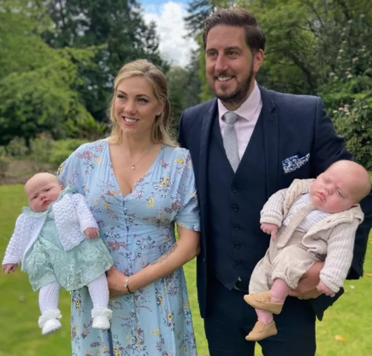 Father playing with twin toddlers in a garden in Cornwall