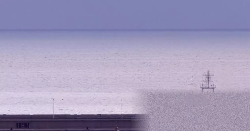A luxury cruise ship anchored off the coast of Tenerife with passengers in protective ponchos being escorted ashore.