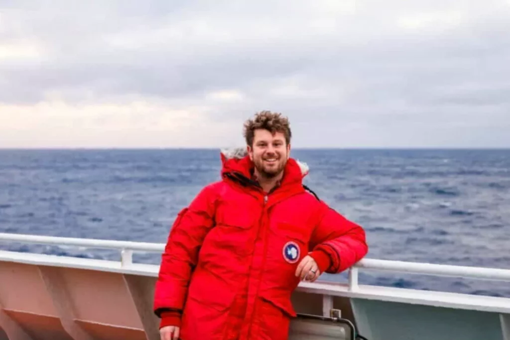 Expedition ship MV Hondius anchored off a remote South Atlantic island with penguins visible onshore