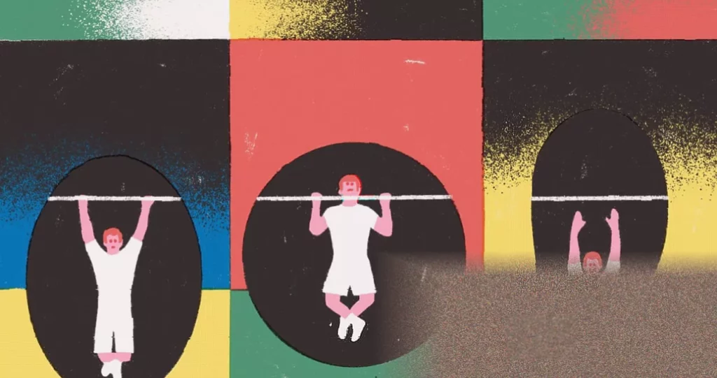 A person performing a pull-up on a metal bar in a gym