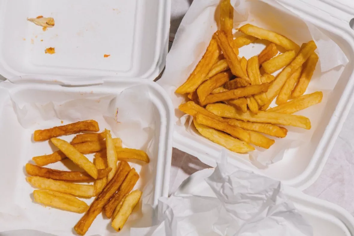 Takeaway food containers on a kitchen table next to a smartphone