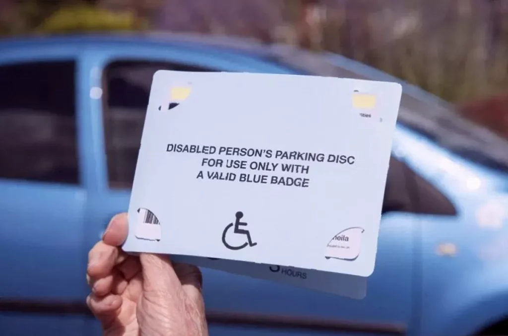 A driver displaying a Blue Badge in a car's windscreen in a UK car park