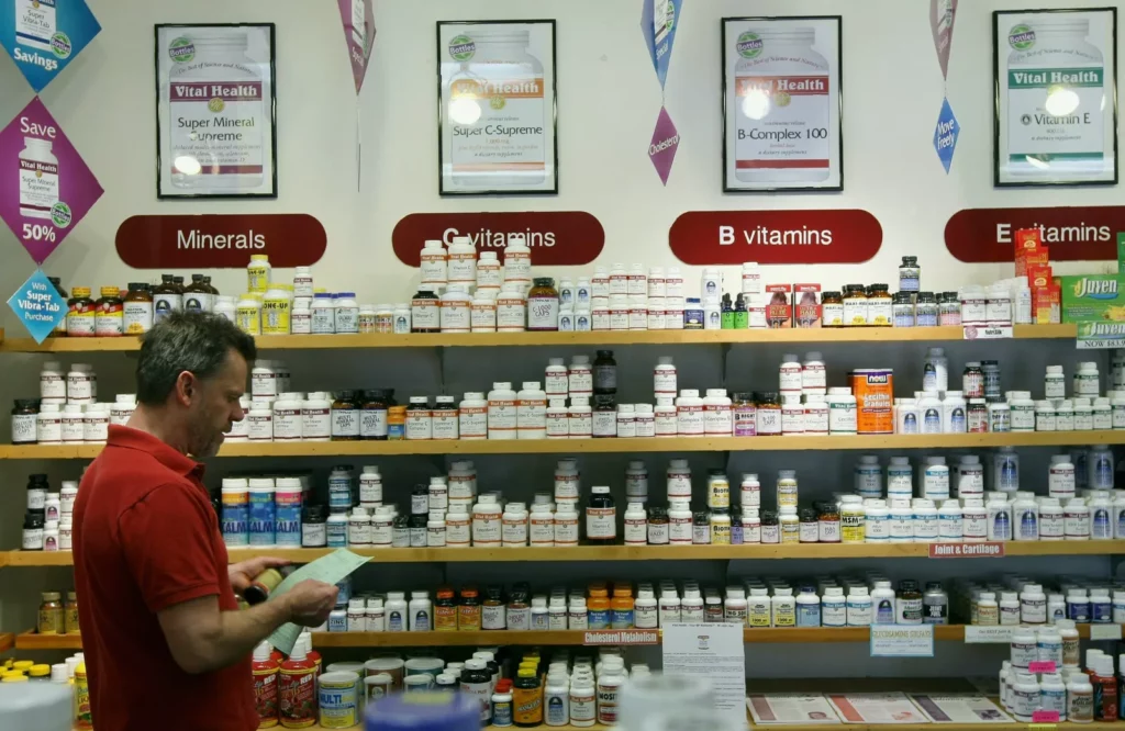 Bottles of liquid multivitamin supplement lined up on a pharmacy shelf