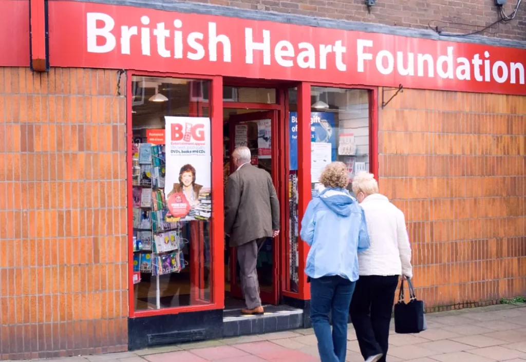 A British Heart Foundation charity shop front on a British high street with closed signage