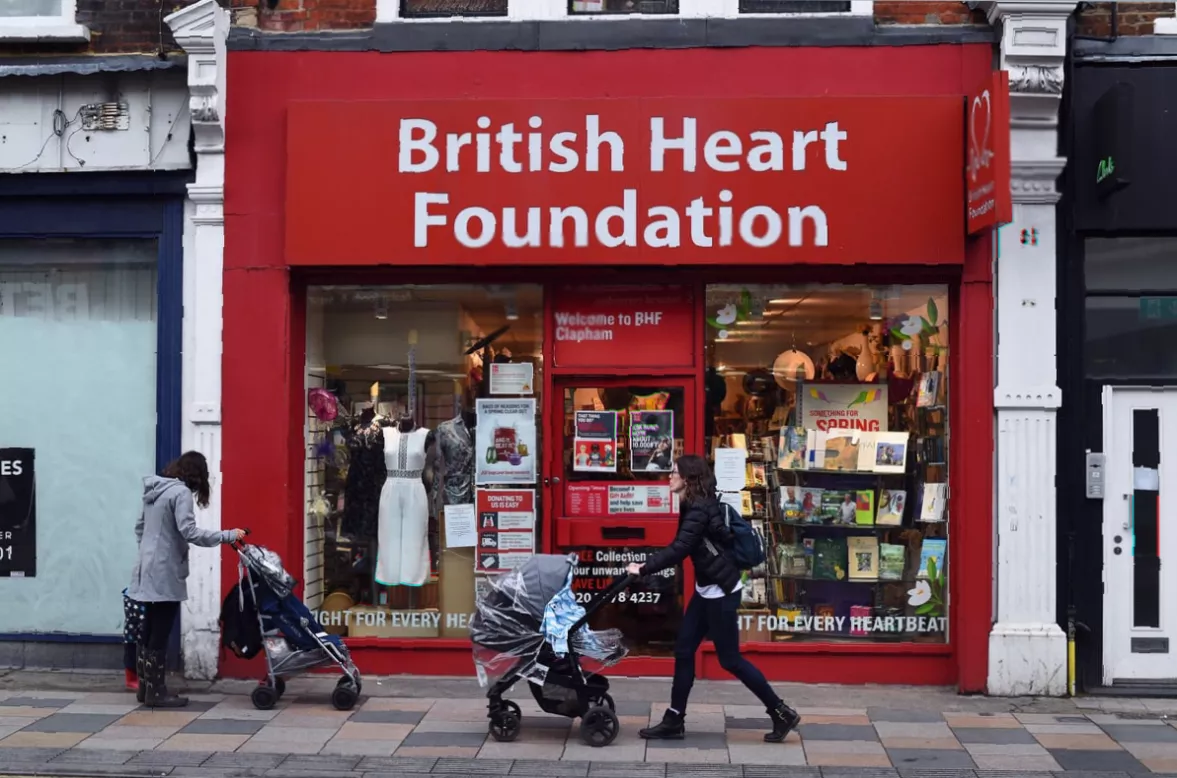Shoppers walking past a row of charity stores in a UK town centre