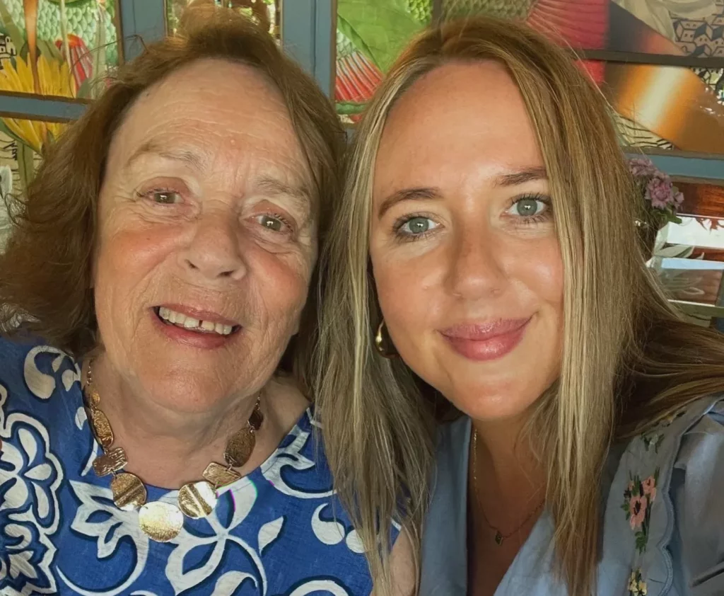 Elderly woman with dementia sitting in a care home garden with a relative nearby