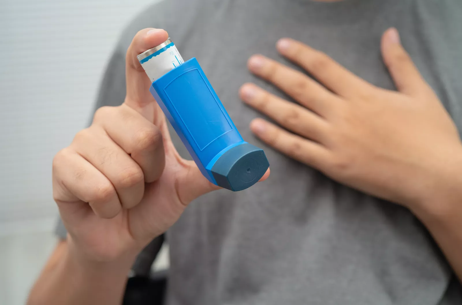 An asthma sufferer shaking an inhaler before use in a home setting