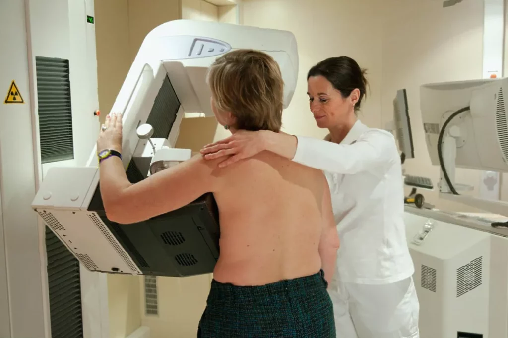 A woman in her thirties looks at a breast cancer awareness poster in a UK clinic.