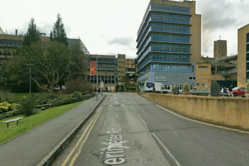 UK airport arrivals hall with public health posters warning about Ebola symptoms