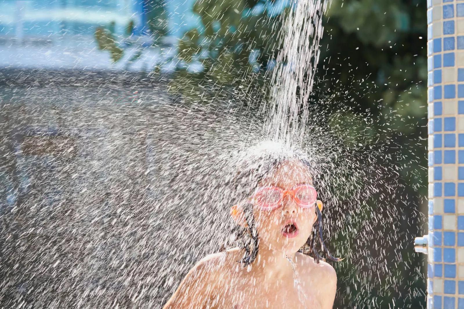 A person walking from changing rooms past shower cubicles toward a pool.