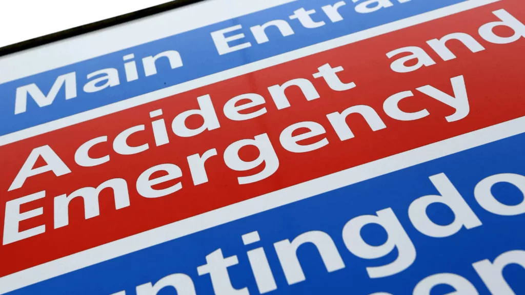 Patients waiting on trolleys in a crowded NHS emergency department corridor