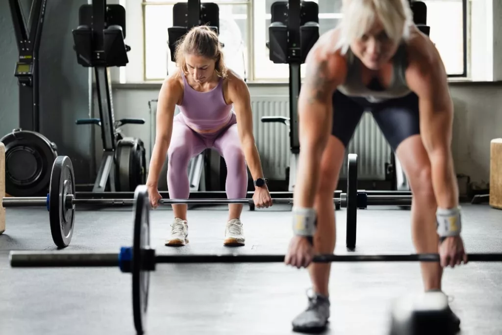 A personal trainer demonstrating a barbell squat in a modern gym setting