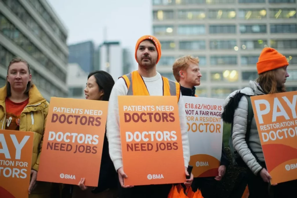 Hospital entrance with a picket line of doctors holding signs outside