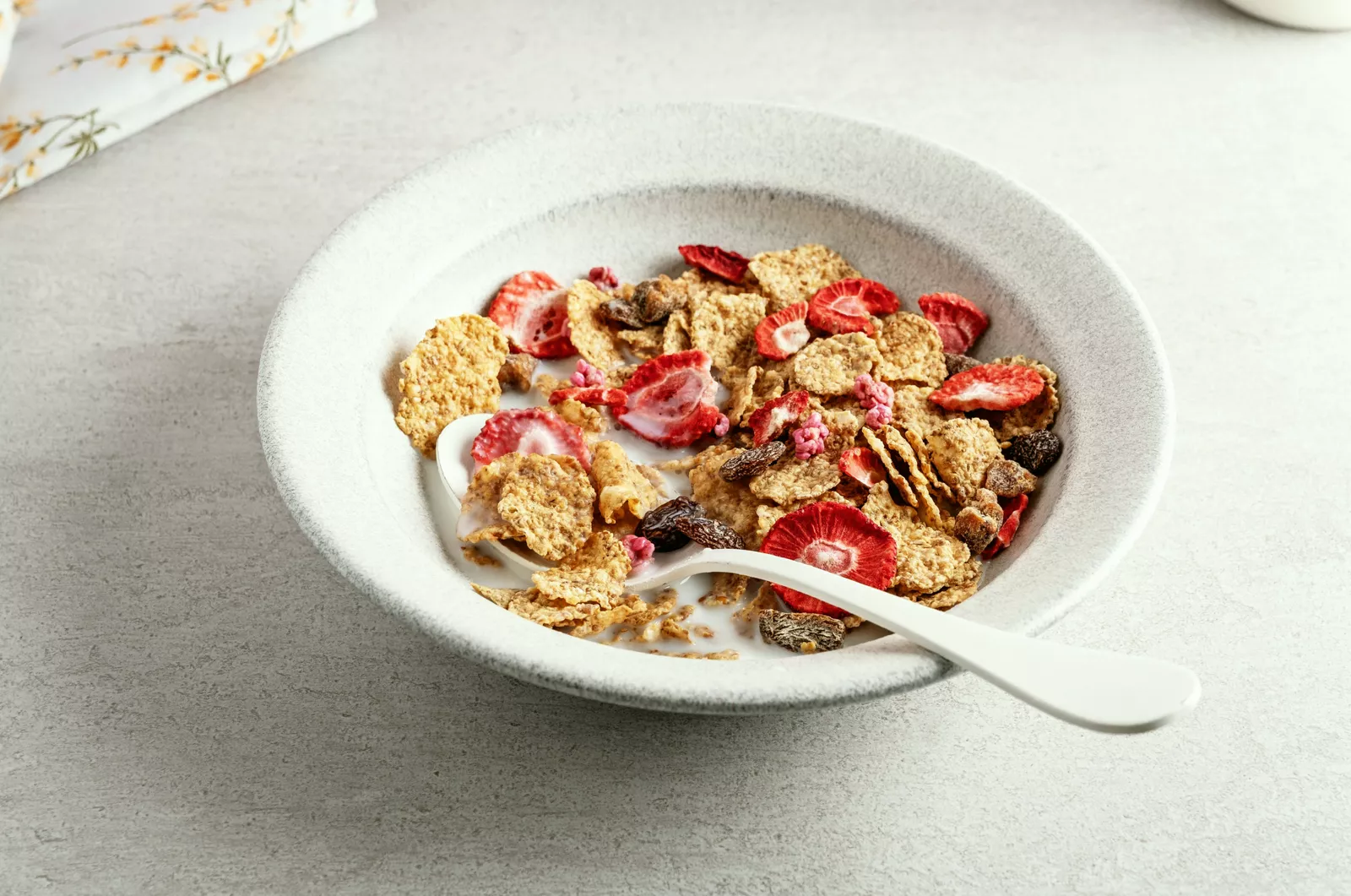 A dining table set with a bowl of overnight oats topped with berries and sliced avocado toast