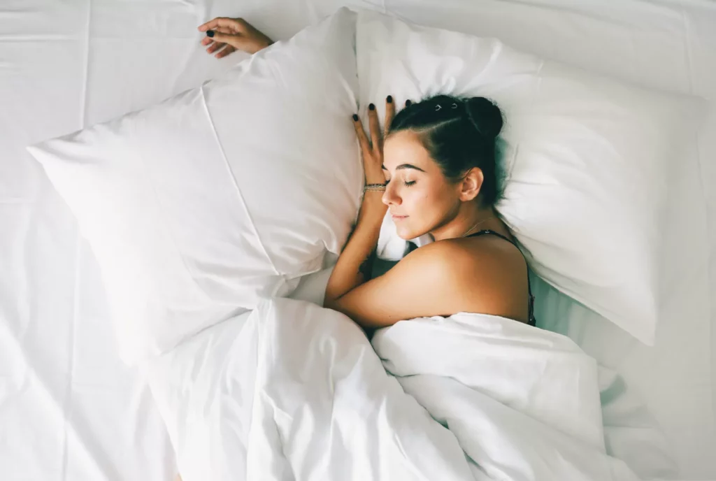 Sleep habit many consider healthy is actually an ominous indicator A person lying in bed at night, wide awake, with a clock showing late hours