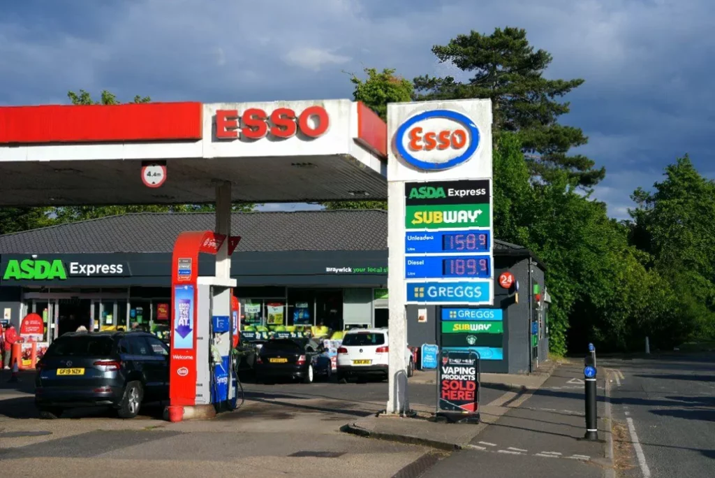 Tenth of employees forgoing meals to afford fuel A driver filling a car at a UK petrol station with a digital price board showing high fuel costs.