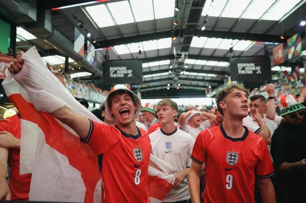 A pub interior in England with a large screen showing a football match before a late-night World Cup kick-off