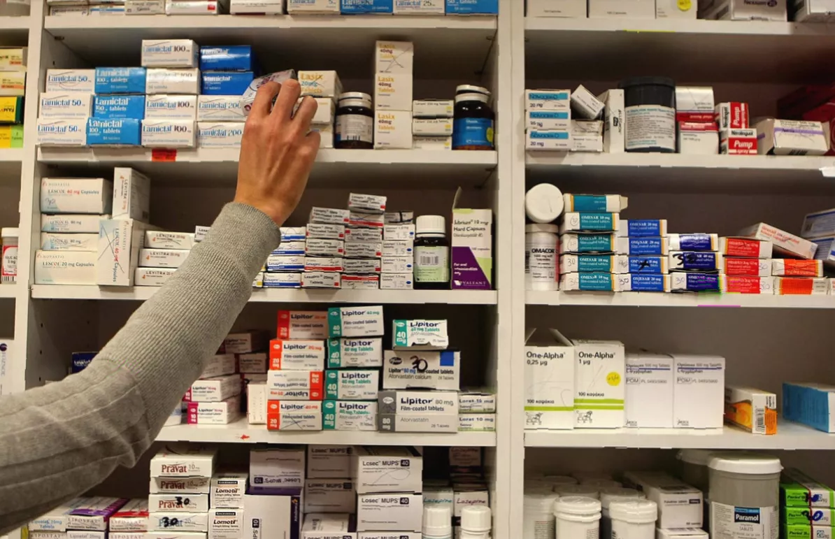 A woman speaking with a pharmacist at a community pharmacy counter