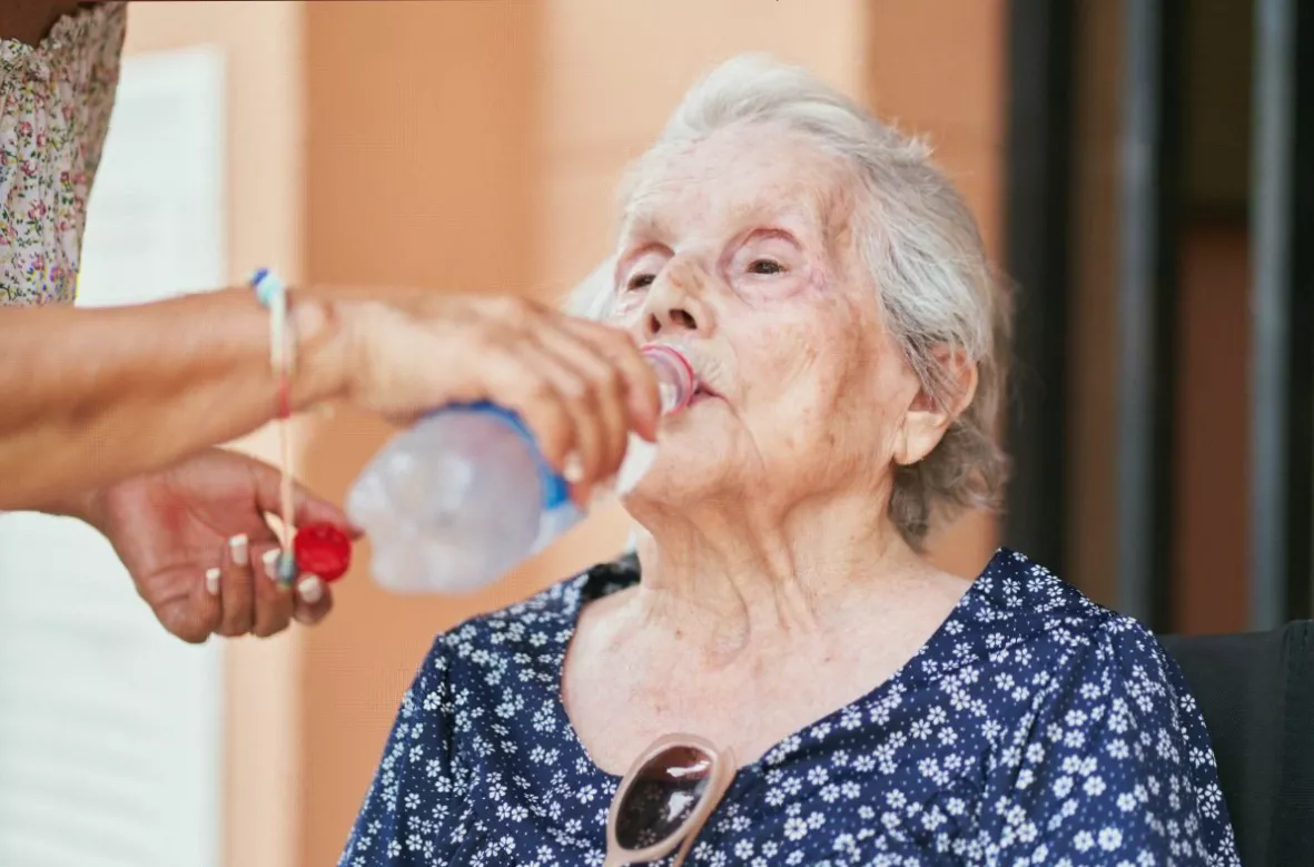Older adult drinking water outdoors in a park setting