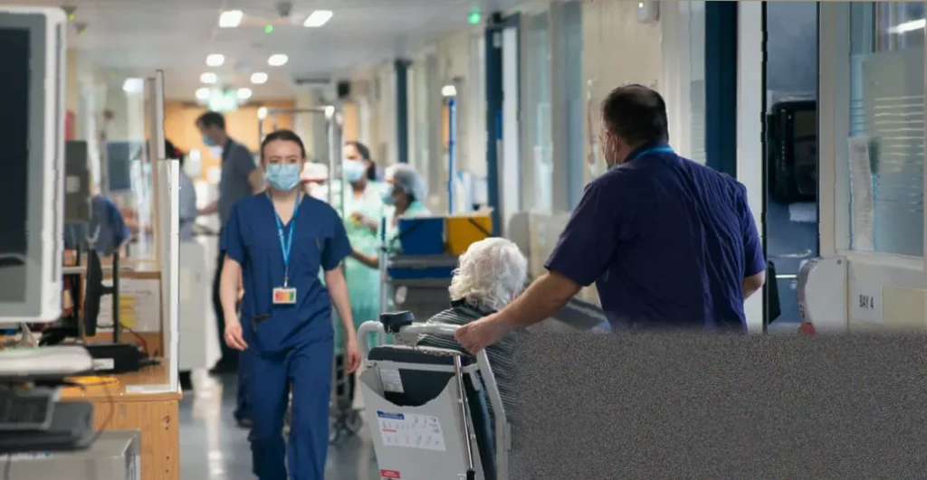 NHS hospital reception desk with staff and patients waiting in a queue