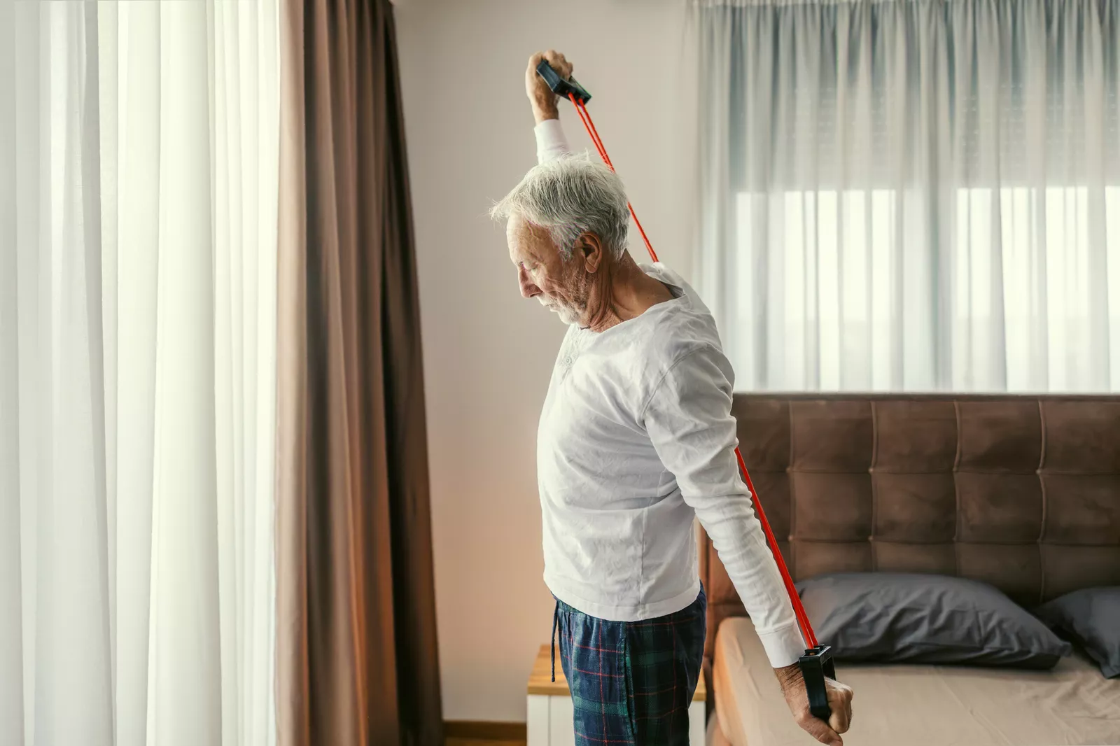 An elderly woman stretching during a group fitness session indoors